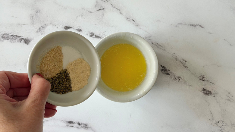 Small bowl of seasonings going into bowl of melted butter