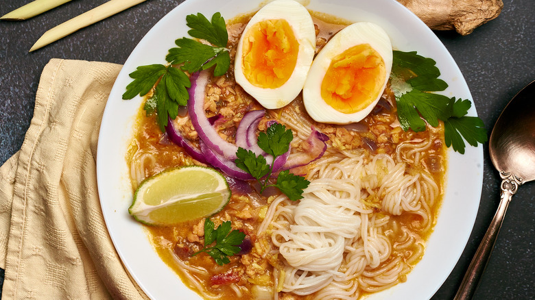 Bowl of mohinga soup with rice noodles, boiled egg, and lime