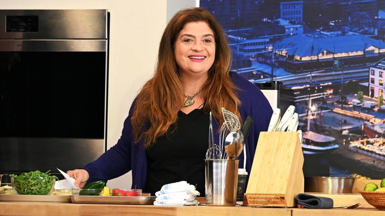 Alex Guarnaschelli standing behind a counter preparing a variety of vegetables