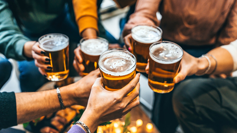 A shot of various hands toasting with glasses of beer