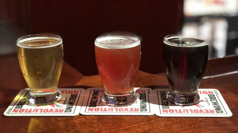 Beer flight of three beers ranging from golden to amber to dark brown on Revolution Brewing coasters