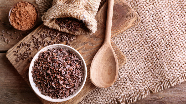 Cocoa nibs in bowl on wood table