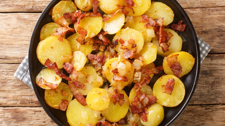 Cottage fries in a plate topped with bacon