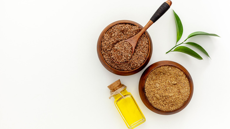 Flaxseeds in wooden bowl next to bottle of oil