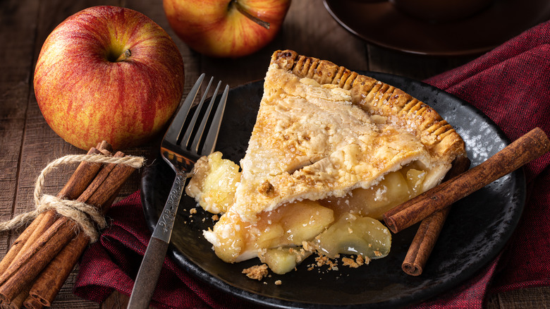 Apple pie slice with cinnamon sticks