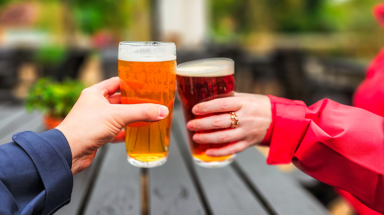 Two hands holding pints of beer in a pub