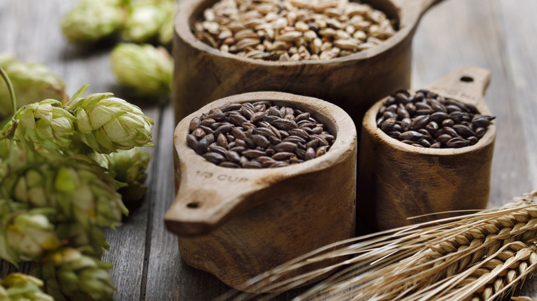 Malt, hops, and grain in wood cups on table