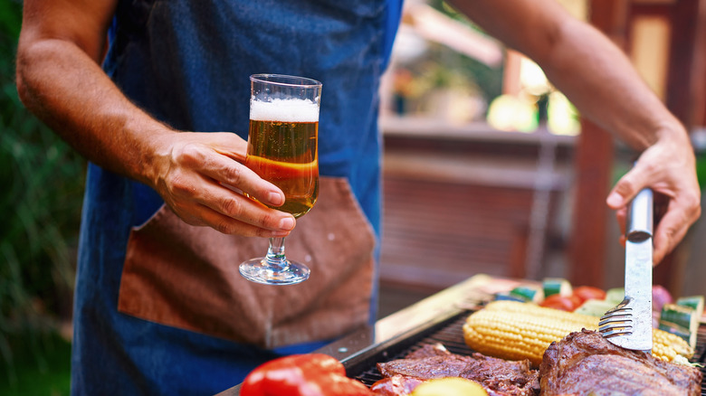 Home cook grilling on a barbecue with beer in hand