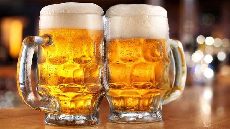 Two mugs of cold beer at a bar.