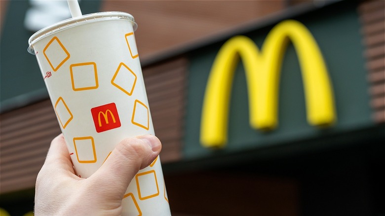 Hand holding McDonald's drink outside restaurant