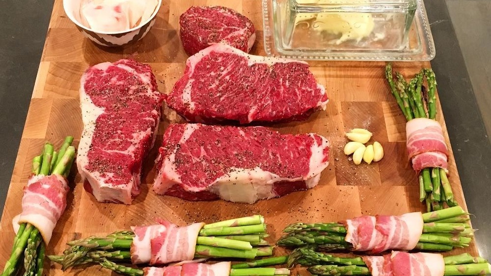 Raw steaks, asparagus, and bacon