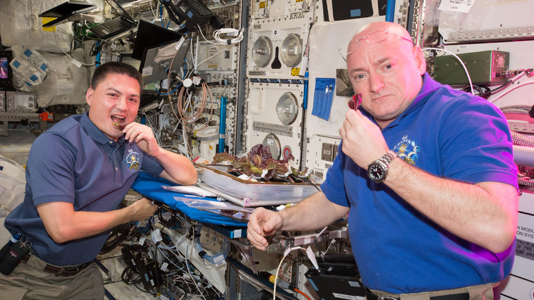 Two astronauts eating on spaceship.