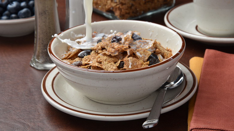 Milk being poured into a bowl of Raisin Bran cereal