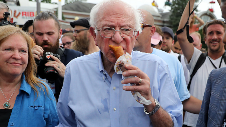 Bernie Sanders holding half-eaten corn dog