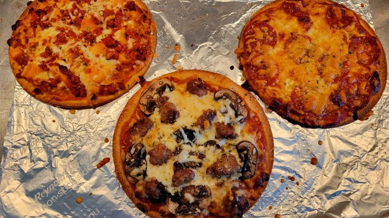 Three cooked Mama Cozzi's mini pizzas on aluminum foil