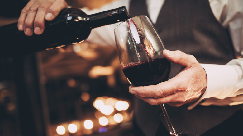 Waiter pouring glass of red wine