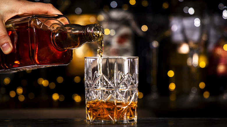 Pouring bourbon into a glass on a bar counter