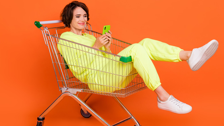 Woman holding cell phone shopping cart