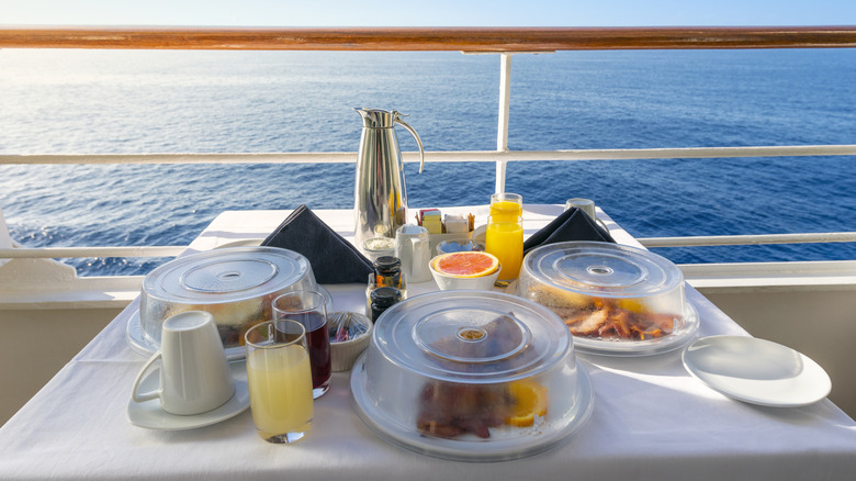 A breakfast meal covered with clear plastic lids on a cruise ship deck