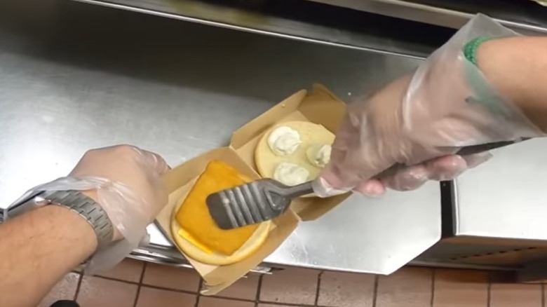The hands of a line worker at McDonald's assembling a freshly cooked Filet-O-Fish