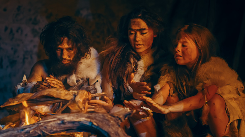 cavemen cooking meat by fire