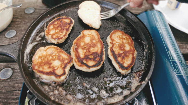 Pancakes being cooked on a cast iron skillet outdoors