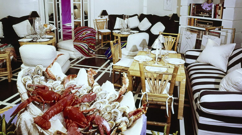 Dinner table laid in '70s living room, with seafood platter in foreground