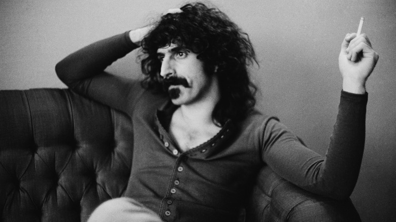 Frank Zappa, smoking a cigarette on a couch