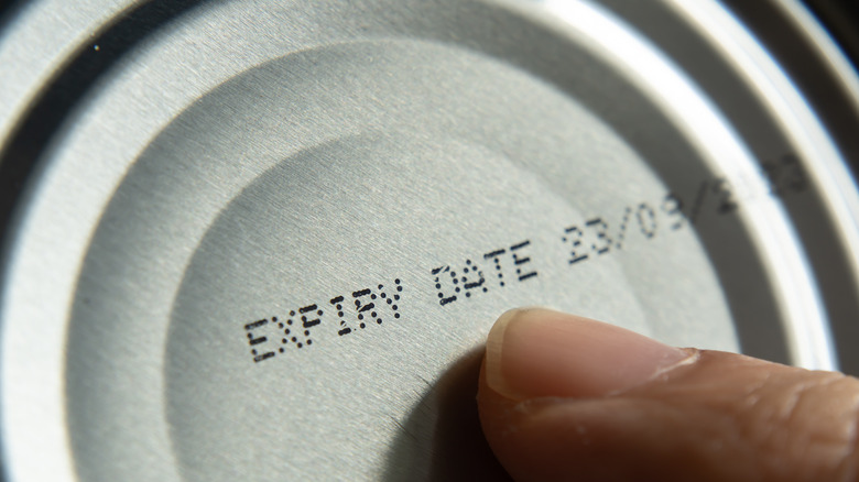 Finger pointing at expiration date on can