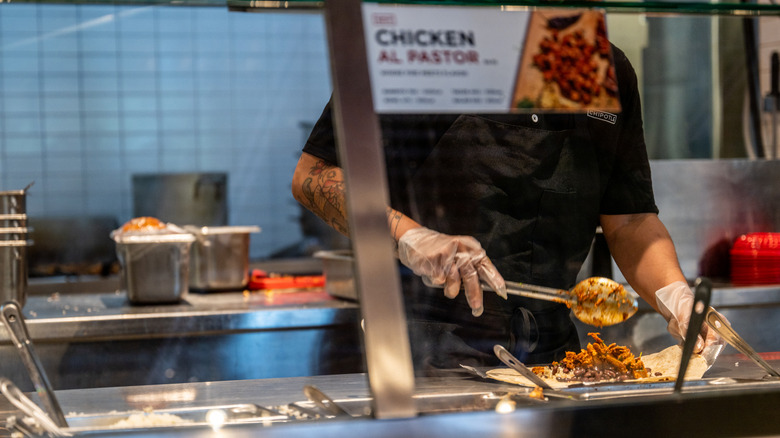 Chipotle employee scooping meat into a bowl