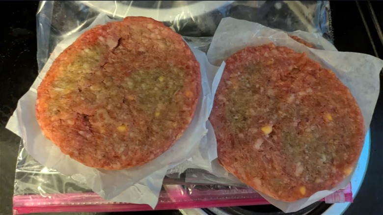 Frozen burger patties with pale green patches.