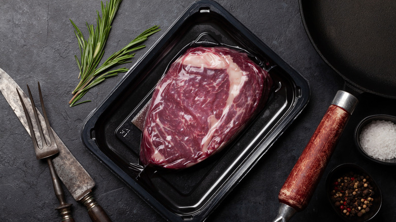 A vacuum-packed steak next to a sprig of rosemary