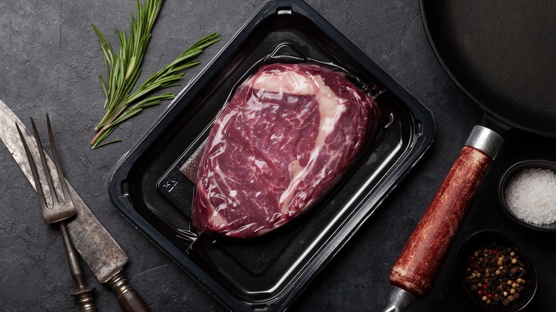 A vacuum-packed steak next to a sprig of rosemary