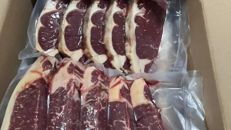 vacuum-sealed steaks with purple coloring in cardboard box