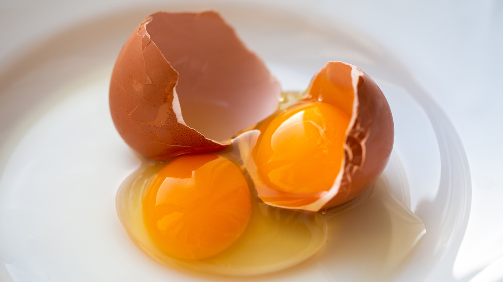 Double yolk egg cracked open on white plate