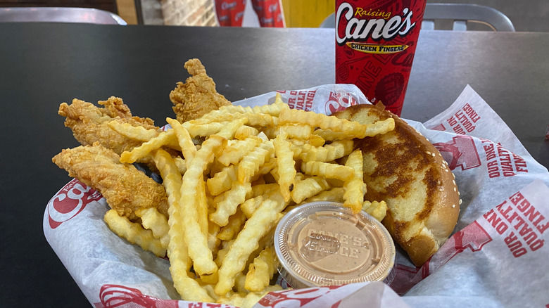 Tray of chicken, fries, and sauce on table at Raising Cane's.