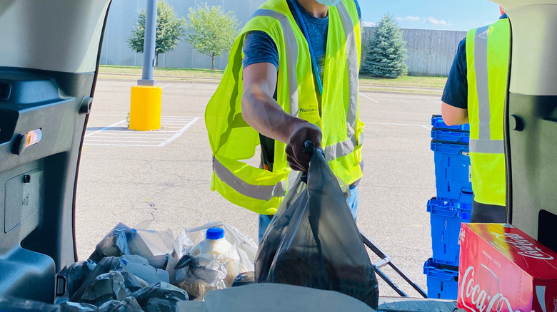 Employees in yellow vests loading groceries in back of vehicle