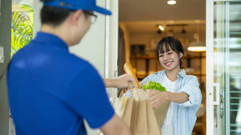 Man delivering groceries to woman standing in doorway