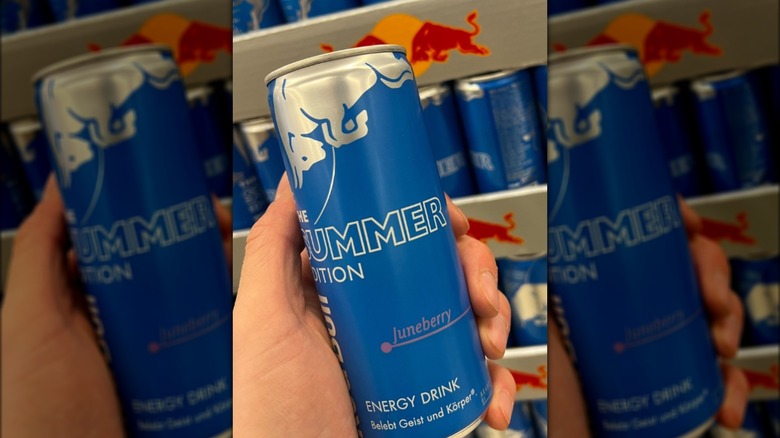 Hand holding juneberry can of Red Bull