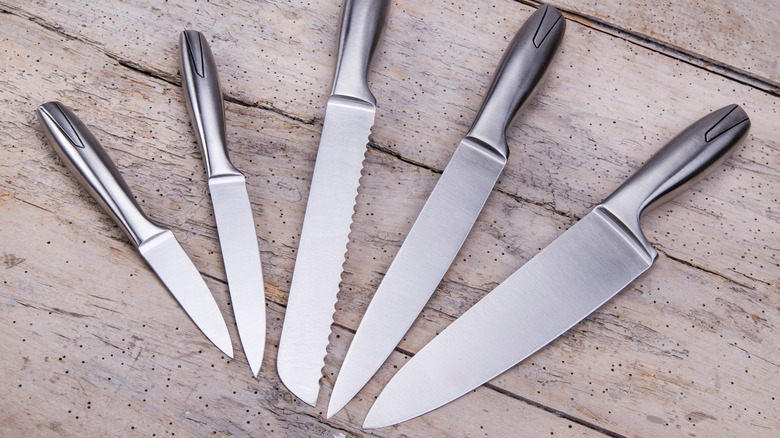 Paring knife alongside other knives on wooden surface