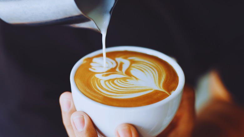 Person pouring cream into coffee