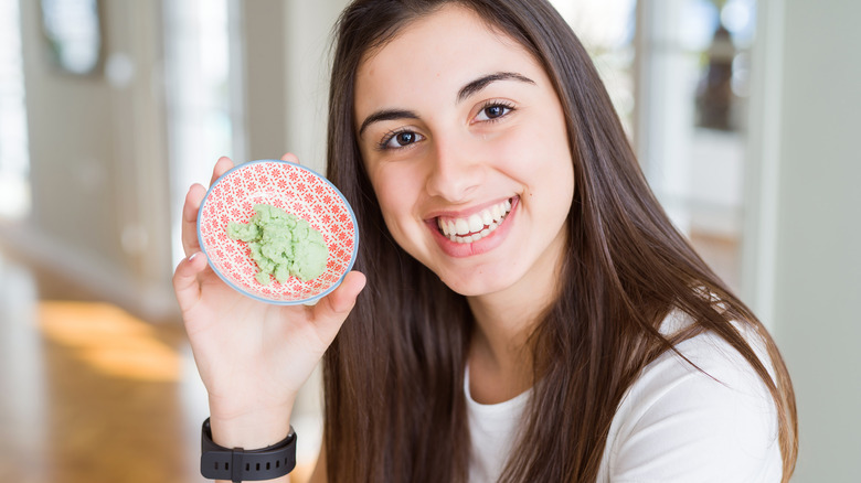 woman holdiing up dish of wasabi and smiling