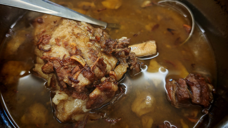 an oxtail stew in a pot with a ladle