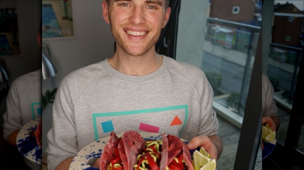 David Atherton smiling and holding a serving of vegan pink tortillas