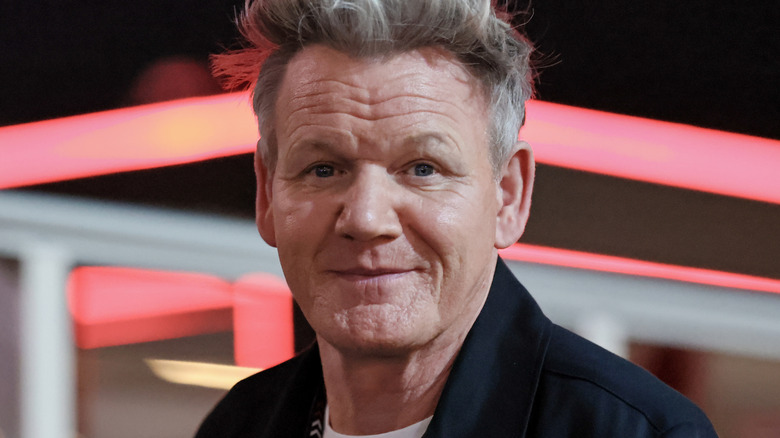 Gordon Ramsay looking at the camera over a dark background with red and white lines
