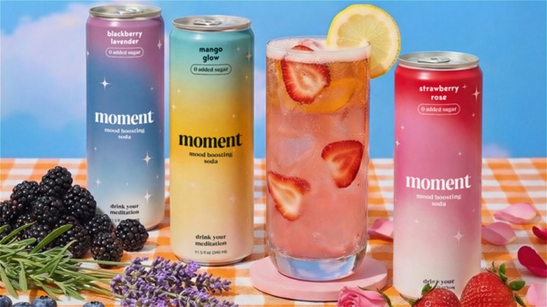 Cans of Moment drinks lined up with fruit