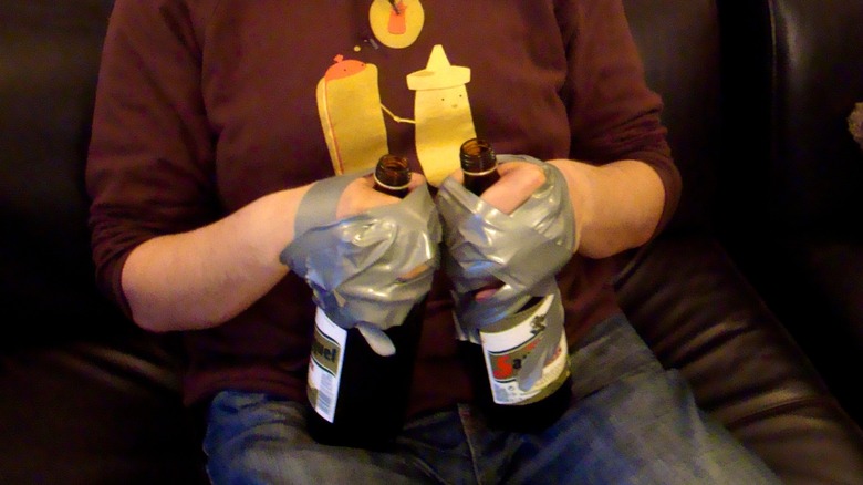 A college student with hands duct taped to 40-oz beers (Edward 40 hands)
