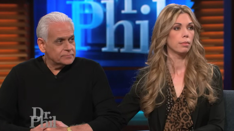 Amy and Samy Bouzaglo sit in chairs in front of the Dr. Phil logo on a TV set