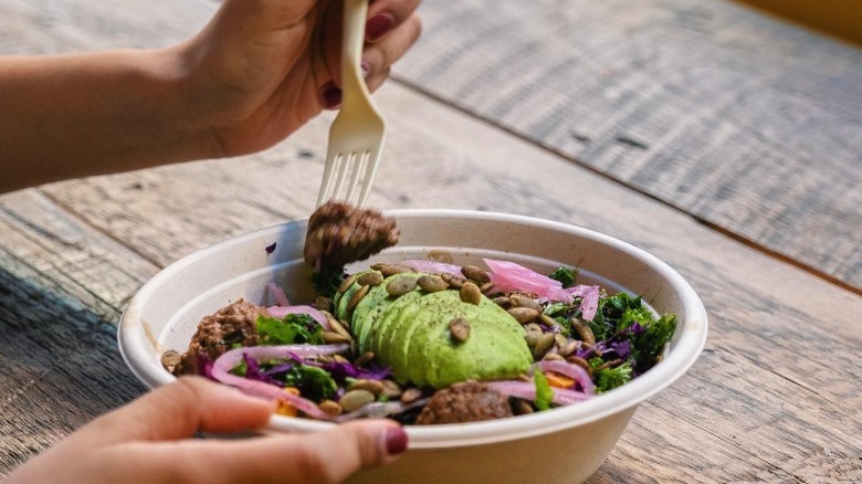   la persona mangia la ciotola di avocado dall'avocaderia