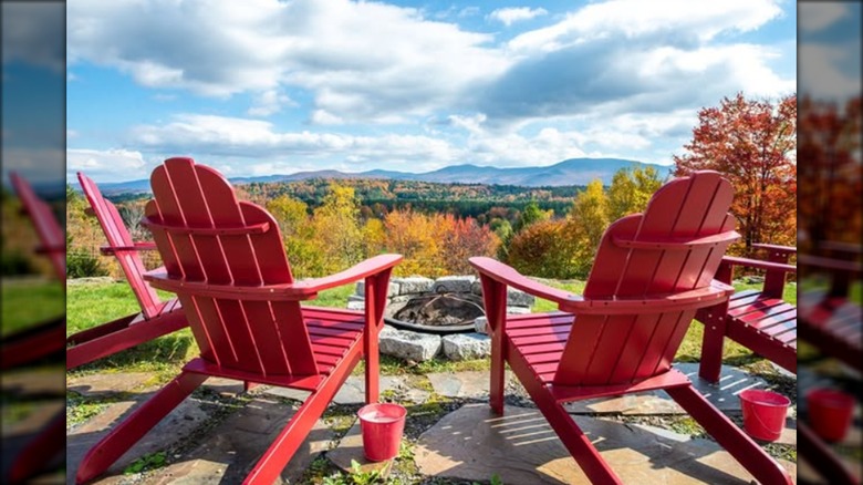 Four red Adirondack chairs around fire pit in front of Vermont landscape